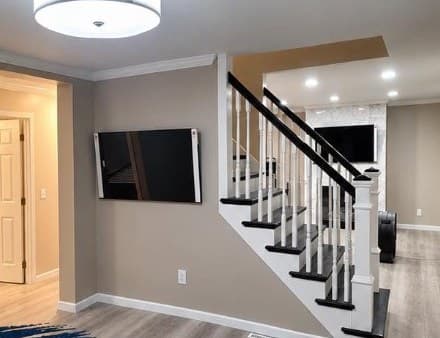 The same room finished with new walls, flooring, and a staircase with white balusters